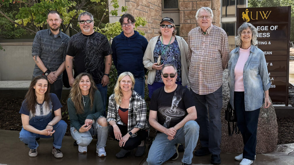Attendees of the 2025 Launch Pad Writers Workshop kneeling outside of the Business Building at the University of Wyoming.